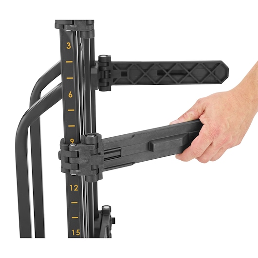 Hand adjusting black arm on photography equipment stand with numbered height scale.