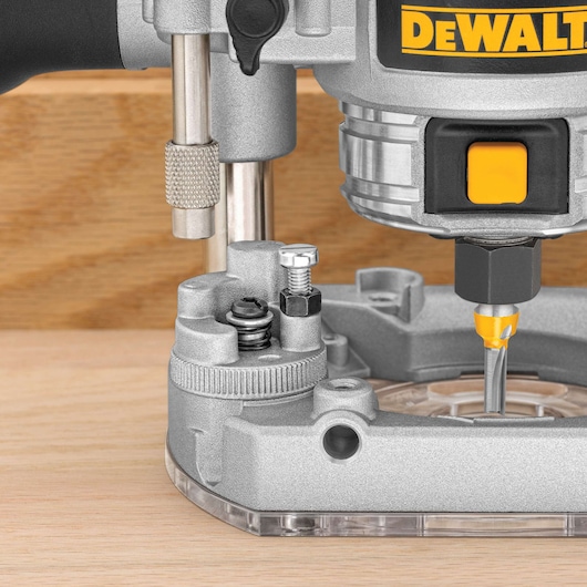Close-up of a DEWALT router on wood, showing the bit and base details.