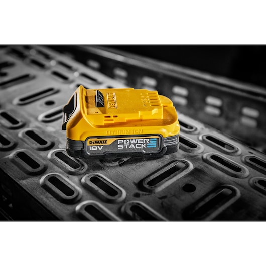 DEWALT 18V POWERSTACK lithium-ion battery shown on a metal surface in close-up view.
