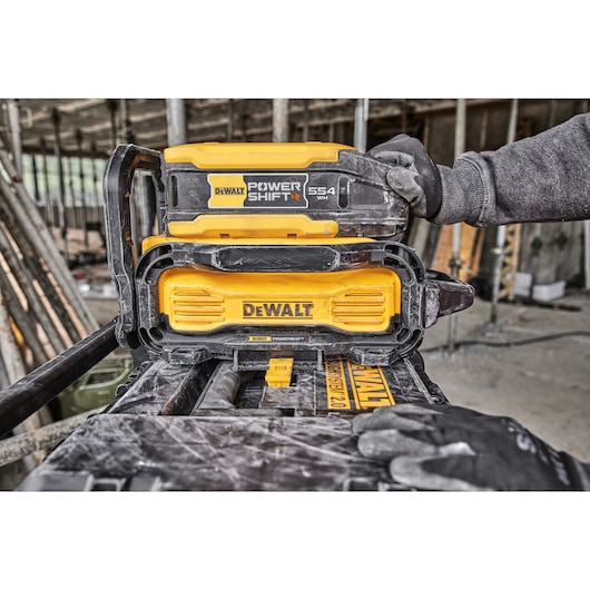 DEWALT PowerShift battery system being used on a construction site, worker's gloved hands are visible.