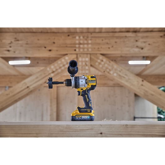 DEWALT cordless drill with hole saw attachment on a wooden surface in a construction setting.