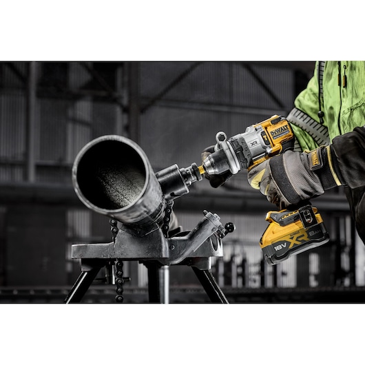 DEWALT DCD1007NT, DCZ607X2-XE drill used on metal pipe in industrial setting. Gloves and battery visible.