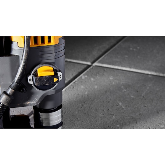 Close-up of a DEWALT tool with yellow and black control, on a tiled concrete surface.