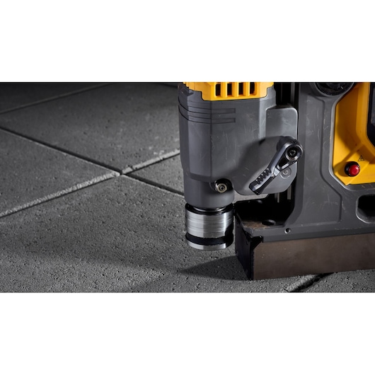 Close-up of DEWALT DCD1623X2G tool on concrete tiles, showing drill attachment and part of the base.