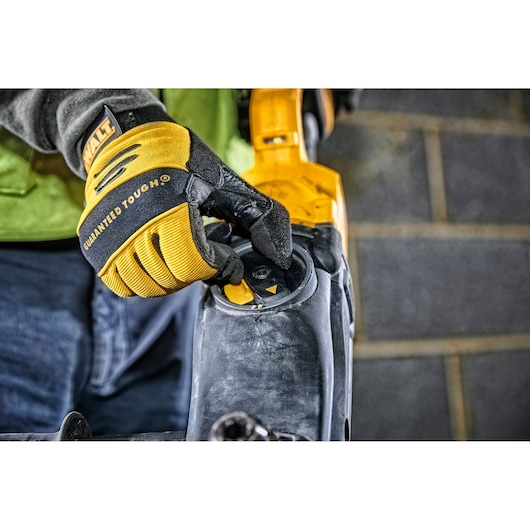 Close-up of a gloved hand adjusting a control dial on a DEWALT power tool.