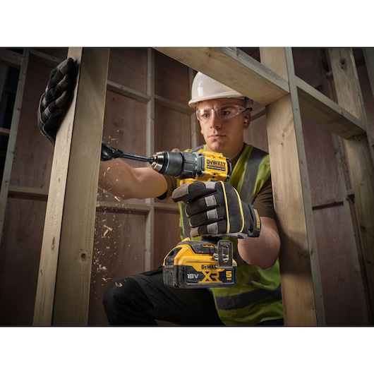 DEWALT drill in use, wood construction. SKUs: DCD794P2T, DCD794P2T-QW. Worker in gloves, blurred face.
