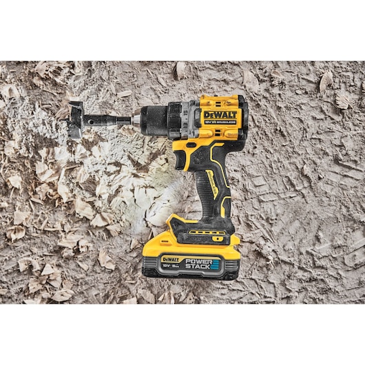 DEWALT cordless drill with POWERSTACK battery shown on a dusty surface with wood shavings.