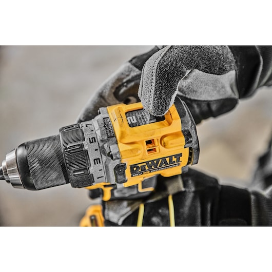 Close-up of a DEWALT DCD800H2T cordless drill in a gloved hand, showing its settings and branding.