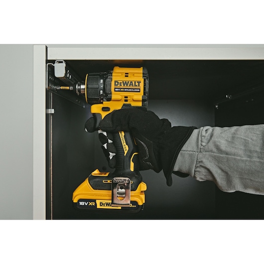 DEWALT drill DCD803NT-XJ, DCD803NT in use inside cabinet. Photography product category. Gloved hand visible.