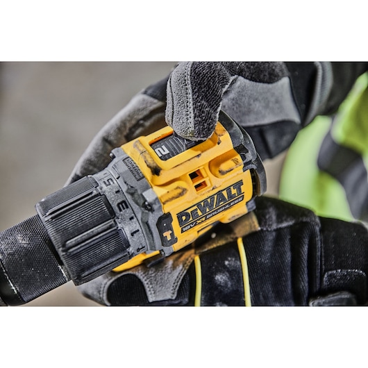 Close-up of a gloved hand adjusting the settings on a DEWALT 18V XR Brushless cordless drill.