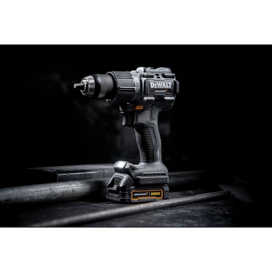 A DEWALT cordless power drill with a black and yellow design, standing upright on a dark industrial surface.