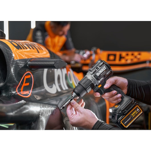 DEWALT cordless drill being used to work on a black and orange race car body.