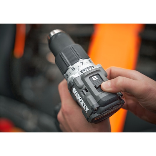 Close-up of DEWALT cordless drill held by hand, showing gear switch and brand logo.