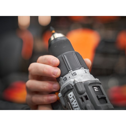 Close-up of a hand holding a DEWALT cordless drill, focus on grip and torque settings.