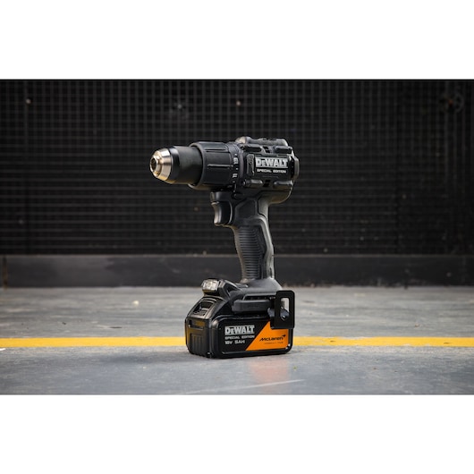 DEWALT drill DCD86MP2T-QW, DCD86MP2T shown on floor. Photography category. Black special edition cordless tool.