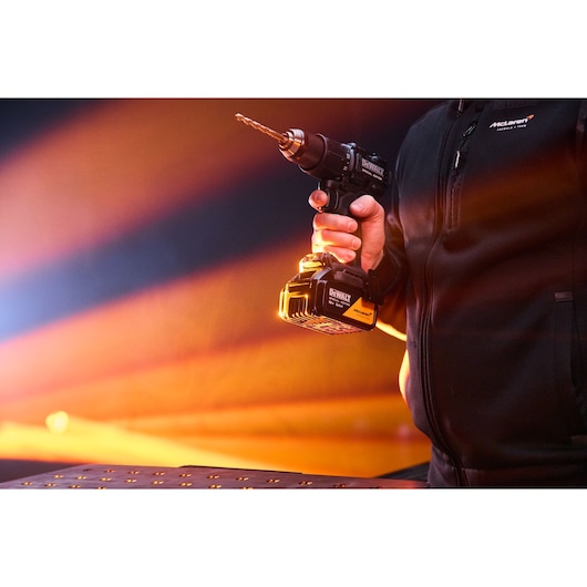 DEWALT drill in hand, Photography category, SKUs DCD86MP2T-QW and DCD86MP2T, with orange lighting background.