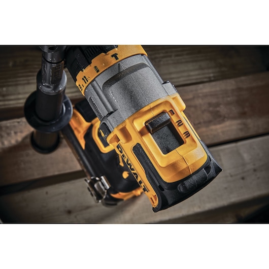 Close-up of a DEWALT cordless power drill showing the speed control switch and part of the handle. The drill features yellow and black accents and is positioned on a wooden surface.