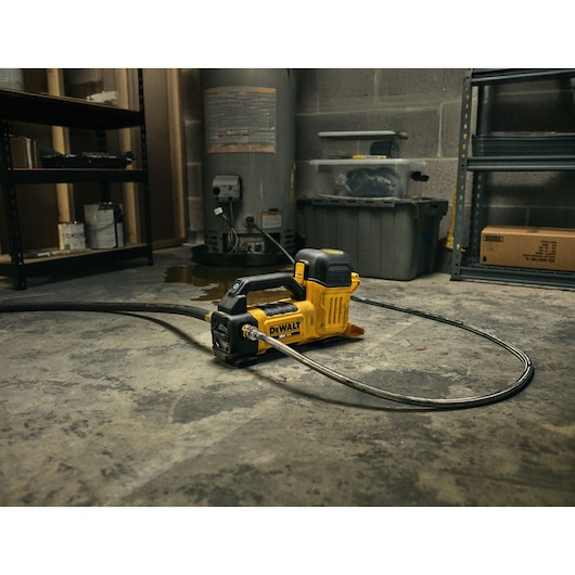 DEWALT DCE050N photography category tool sits on a workshop floor, attached to hose, surrounded by shelves.