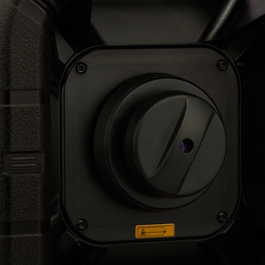 Close-up of a black DEWALT device with a round dial and yellow warning label.