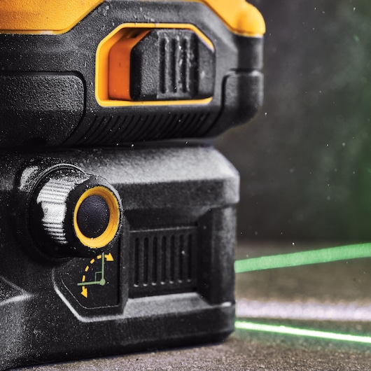 Close-up of a DEWALT laser level with adjustment knob and visible green laser line.