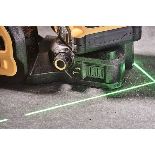 Close-up of DEWALT laser level projecting bright green lines on a stone surface.