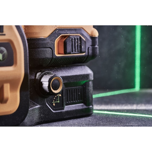 Close-up of a DEWALT laser level tool projecting bright green laser lines on a dark surface.
