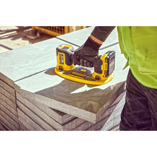 Worker uses a DEWALT cordless tool to lift concrete slabs at a construction site.