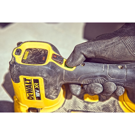 Close-up of a gloved hand using a DEWALT 18V XR power tool with yellow and black casing.