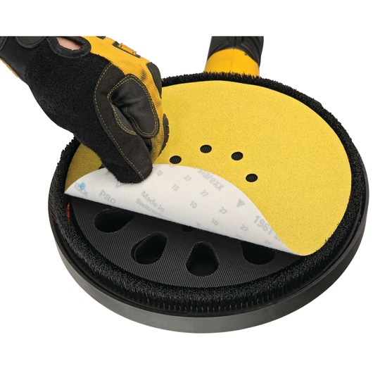 Gloved hand places sanding disc onto DEWALT DCE800N sander. Close-up of tool and abrasive pad.
