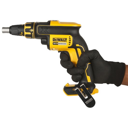 A person wearing a black glove is holding a yellow and black DEWALT 18V XR brushless cordless screwdriver against a white background.