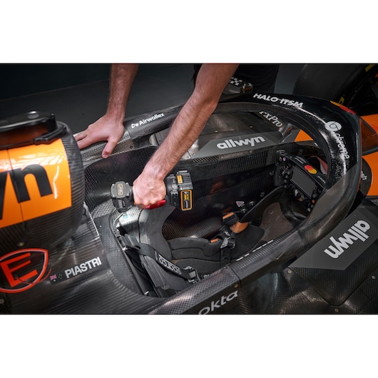 Person uses a DEWALT tool inside a racing car cockpit, showing detailed interior and seat.