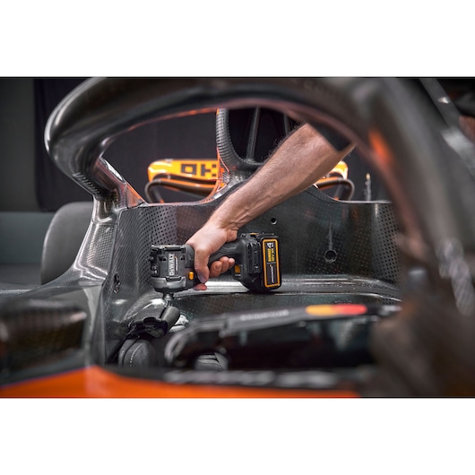 Person uses DEWALT cordless tool inside a carbon fiber vehicle cockpit.