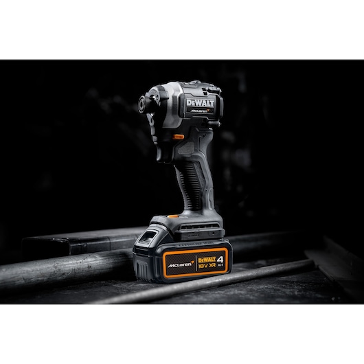 DEWALT McLaren 18V XR cordless impact driver with 4Ah battery on a dark industrial surface.