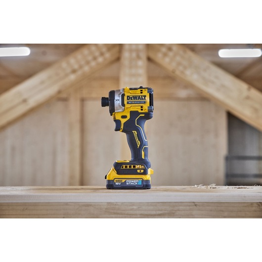DEWALT cordless impact driver displayed upright on a wooden surface at a construction site.