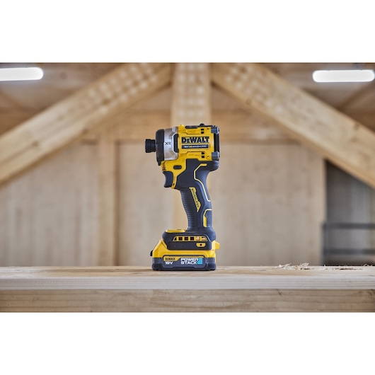 DEWALT cordless impact driver displayed upright on a wooden surface at a construction site.