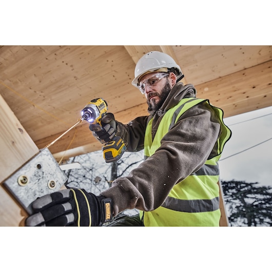 Worker uses DEWALT DCK2201P1T1-XE, DCF860NT drill at construction site. Photography product category.