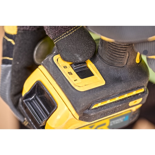 Close-up of a gloved hand adjusting a DEWALT power tool speed setting switch.