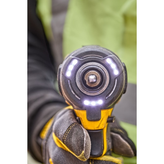 Close-up of a DEWALT power tool with LED lights, held by a gloved hand.