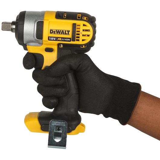 A person wearing a black glove is holding a DEWALT 18V XR Li-ion cordless impact wrench. The tool is yellow and black and features a metal belt clip.