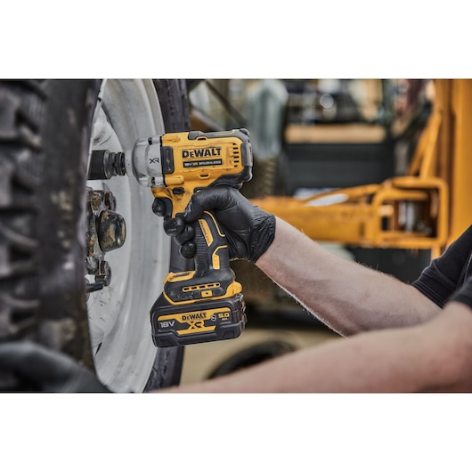 DEWALT cordless impact wrench used to loosen lug nuts on a vehicle wheel.