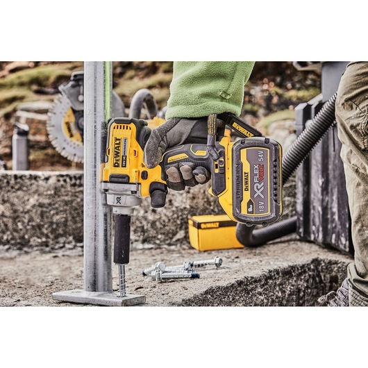 Close-up of DEWALT DCF894P2 impact wrench being used on a metal structure outdoors.