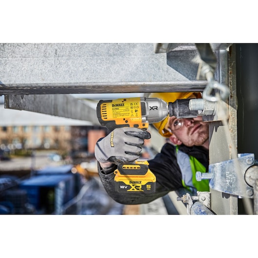 DEWALT DCF900NT-XJ, DCF900NT impact wrench in use on site. Construction worker tightens bolt with tool.