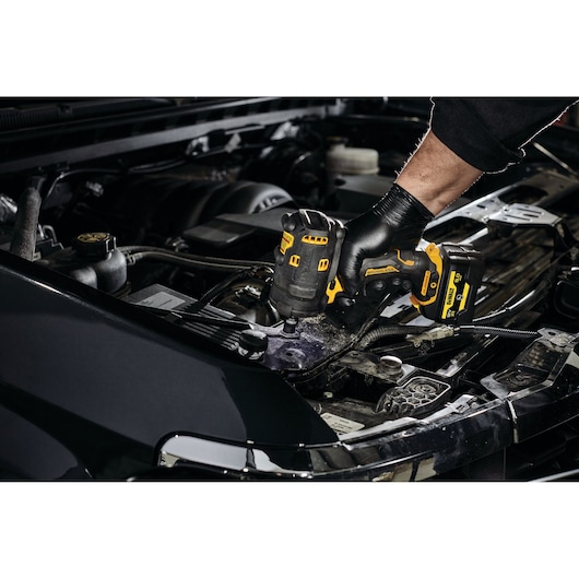 DEWALT DCF901P1G-QW, DCF901P1G impact driver used on car engine. Photography product category.
