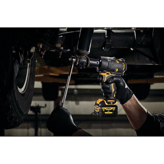DEWALT DCF901P1G-QW, DCF901P1G impact wrench used under vehicle. Photography product for automotive work.
