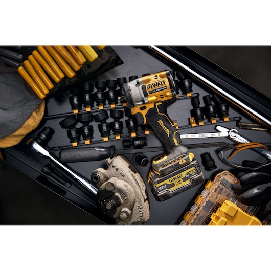 A DEWALT 18V XR cordless impact wrench (model DCF923P2G) is placed in a tool drawer surrounded by various sockets, wrenches, and other hand tools. The tools are organized in a workshop environment.