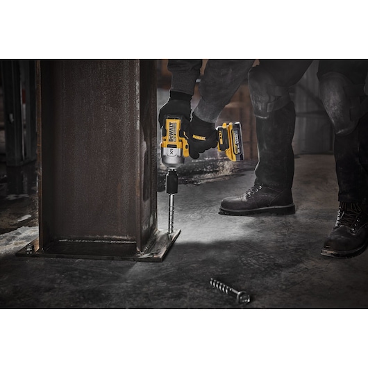 Person uses DEWALT cordless impact wrench DCF961H2T to fasten bolt to steel column on industrial site.