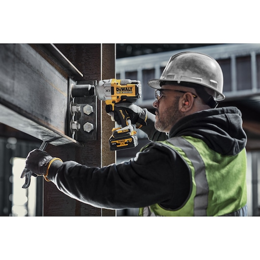 DEWALT DCF961N, DCF961N-XJ impact wrench used on bolts in industrial setting. Photography category.