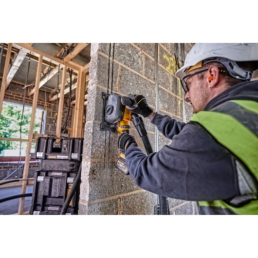 Worker uses DEWALT DCG200T2 tool to cut into a concrete wall at a construction site.