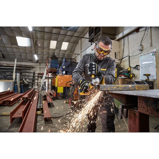 DEWALT DCG404NT, DCG404S2T-QW grinding metal in workshop, sparks flying, photography category.