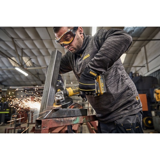 DEWALT DCG404S2T-QW, DCG404S2T grinder sparks while cutting metal in workshop. Photography product category.